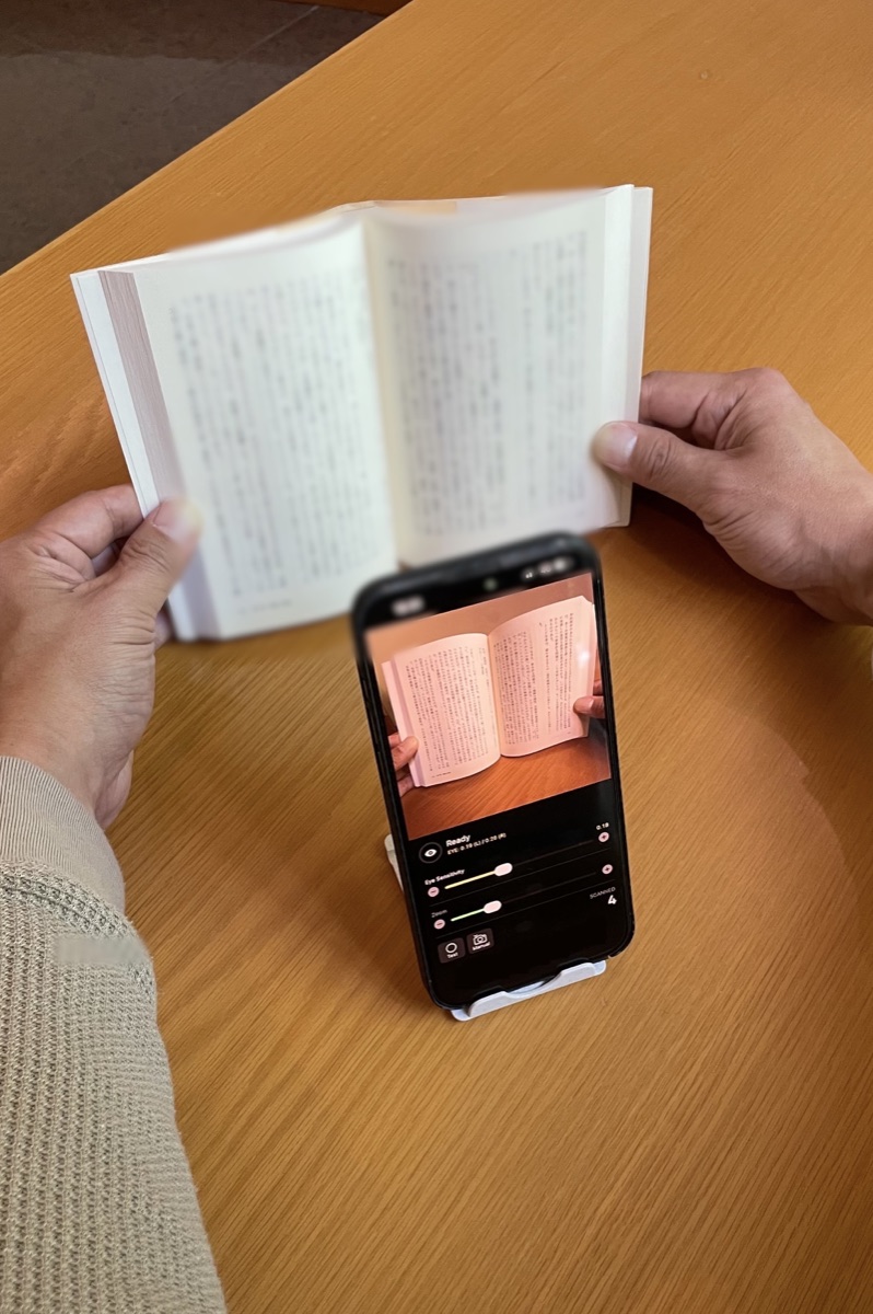 両手で本を押さえながらPachiSCAでまばたきスキャンしている実演風景 / Hands-free book scanning with PachiSCA